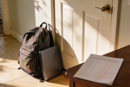 A high school backpack and laptop case by the front door on the first morning of term.