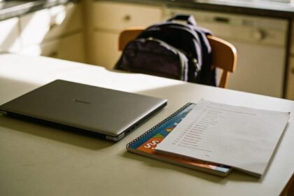 A laptop and a school list on a kitchen table before the start of the school year.