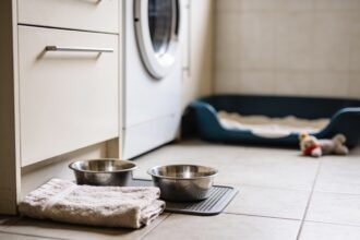 A puppy sleeping area set up with a bed, stainless steel bowls and a towel before the puppy arrives.