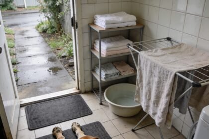 A mat, clean towels and empty basin beside a back door, with a used towel spread on a drying rail.