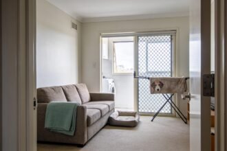 A tidy living room with a folded sofa throw, dog bed and pet blanket drying in the adjoining laundry.