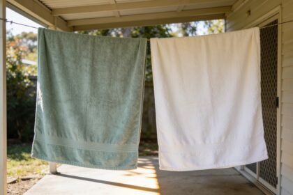 Two cotton bath towels hanging separately on a clothesline under a shaded verandah.