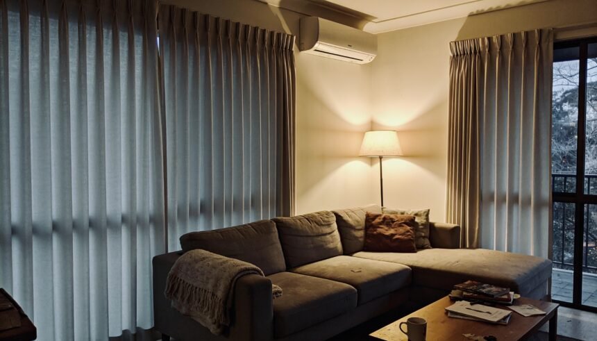 An Australian living room in winter with curtains drawn and a wall-mounted reverse cycle unit.
