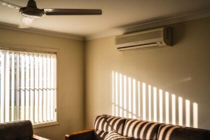 A living room with blinds drawn and a ceiling fan running on a hot summer afternoon.