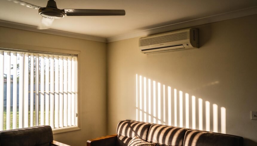 A living room with blinds drawn and a ceiling fan running on a hot summer afternoon.
