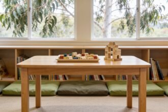Building pieces on a child-height table beside low bookshelves and cushions in a public library.