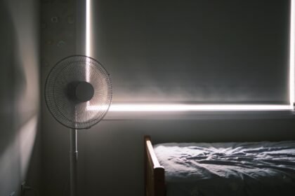 A child's bedroom with a blockout blind down over the window and a pedestal fan in the corner.