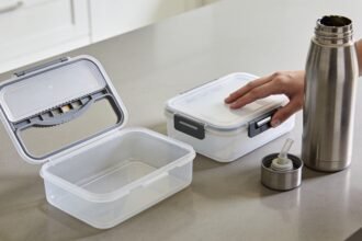 Lunchboxes and a drink bottle laid open on a kitchen bench while their seals and clips are checked.