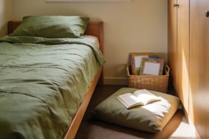 Floor cushion and book basket beside a single bed, with space to reach the bedroom door and wardrobe.