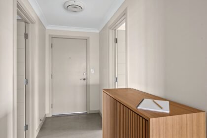 A home entry hallway with a ceiling smoke alarm and a notebook on a timber console.